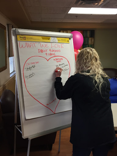 A participant engages in a collaborative brainstorming session, writing ideas on a heart-shaped flip chart.