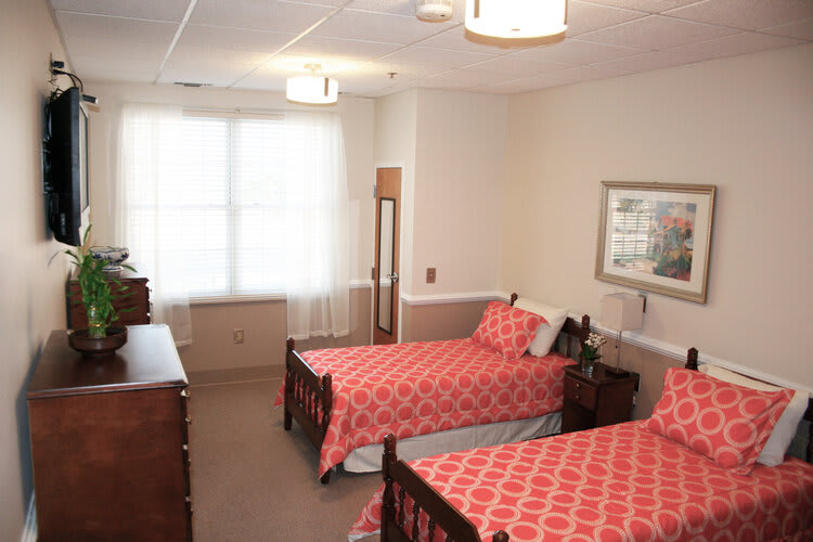 A cozy bedroom with twin beds and matching red patterned bedspreads.