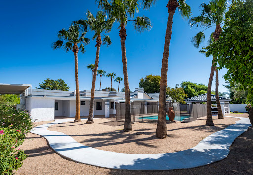 A serene residential property featuring palm trees, a swimming pool, and modern design under a clear blue sky.