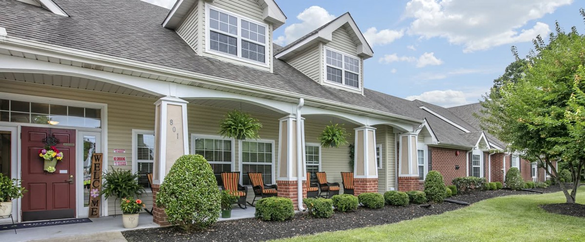 A charming residential house with a spacious front porch and greenery.