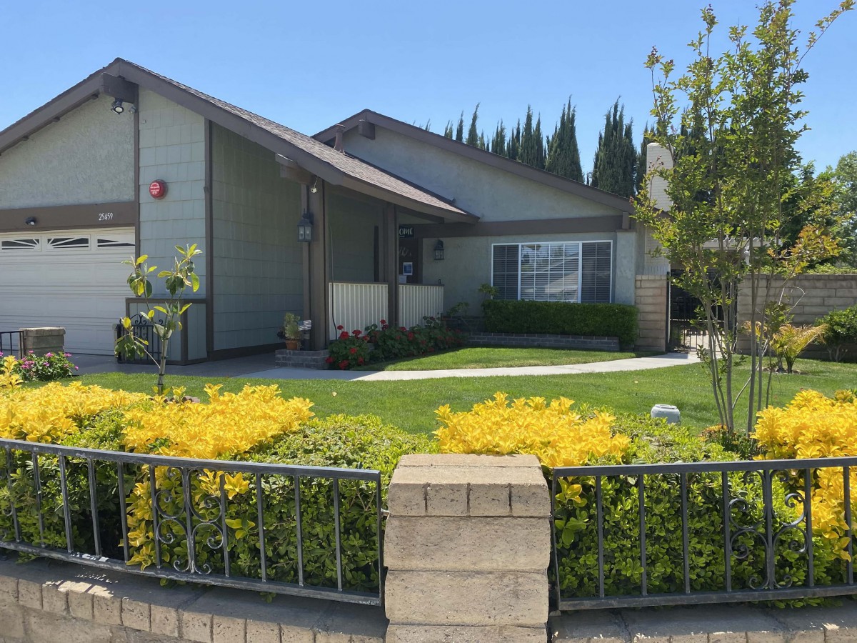 A well-maintained suburban house with a green lawn and garden.