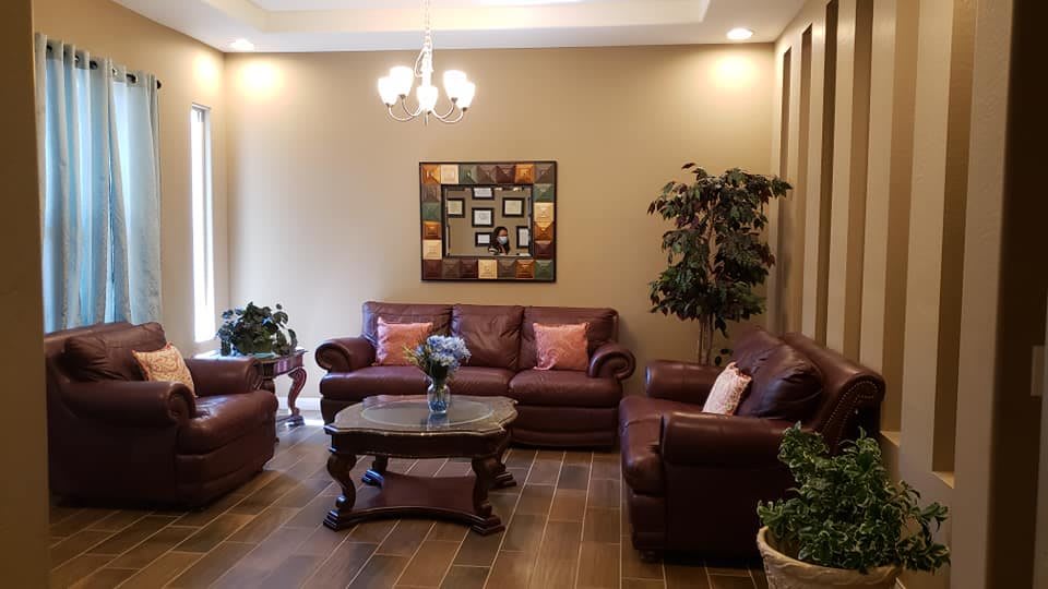 A cozy living room with brown sofas, a coffee table, indoor plants, and decorative artwork.
