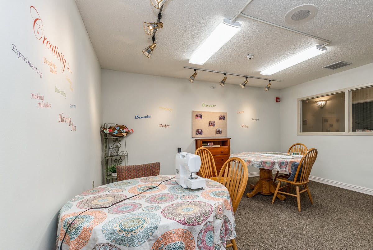 A cozy craft room featuring tables with sewing machines and decorated walls.