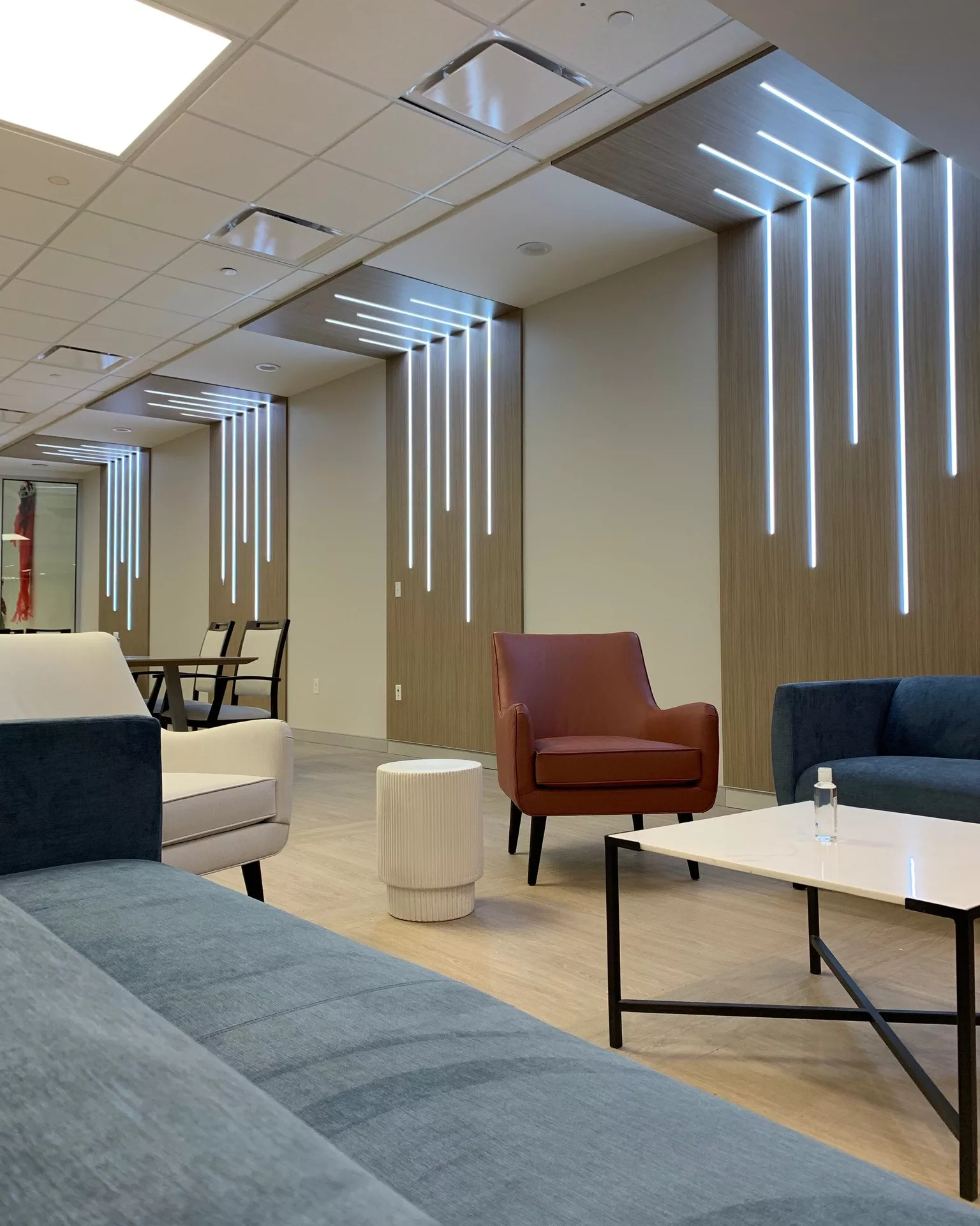 A modern office lounge area with comfortable seating and sleek lighting fixtures.