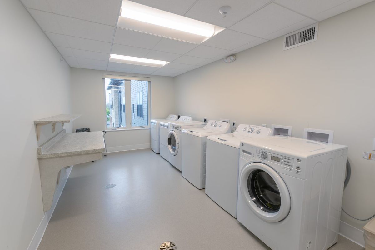 A clean and organized laundry room with several washing machines and dryers.