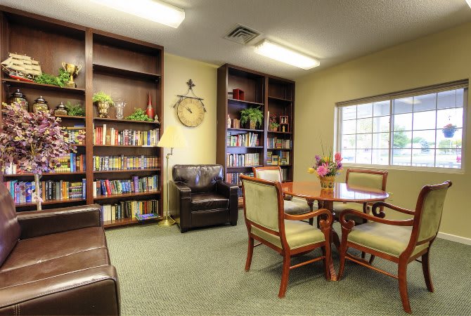 A cozy library room with bookshelves, a reading table, and comfortable seating.