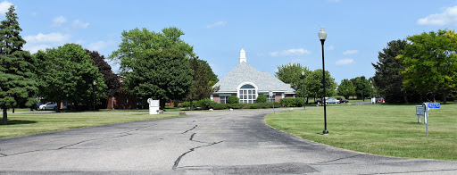 A serene view of a modern building surrounded by greenery under a clear blue sky.
