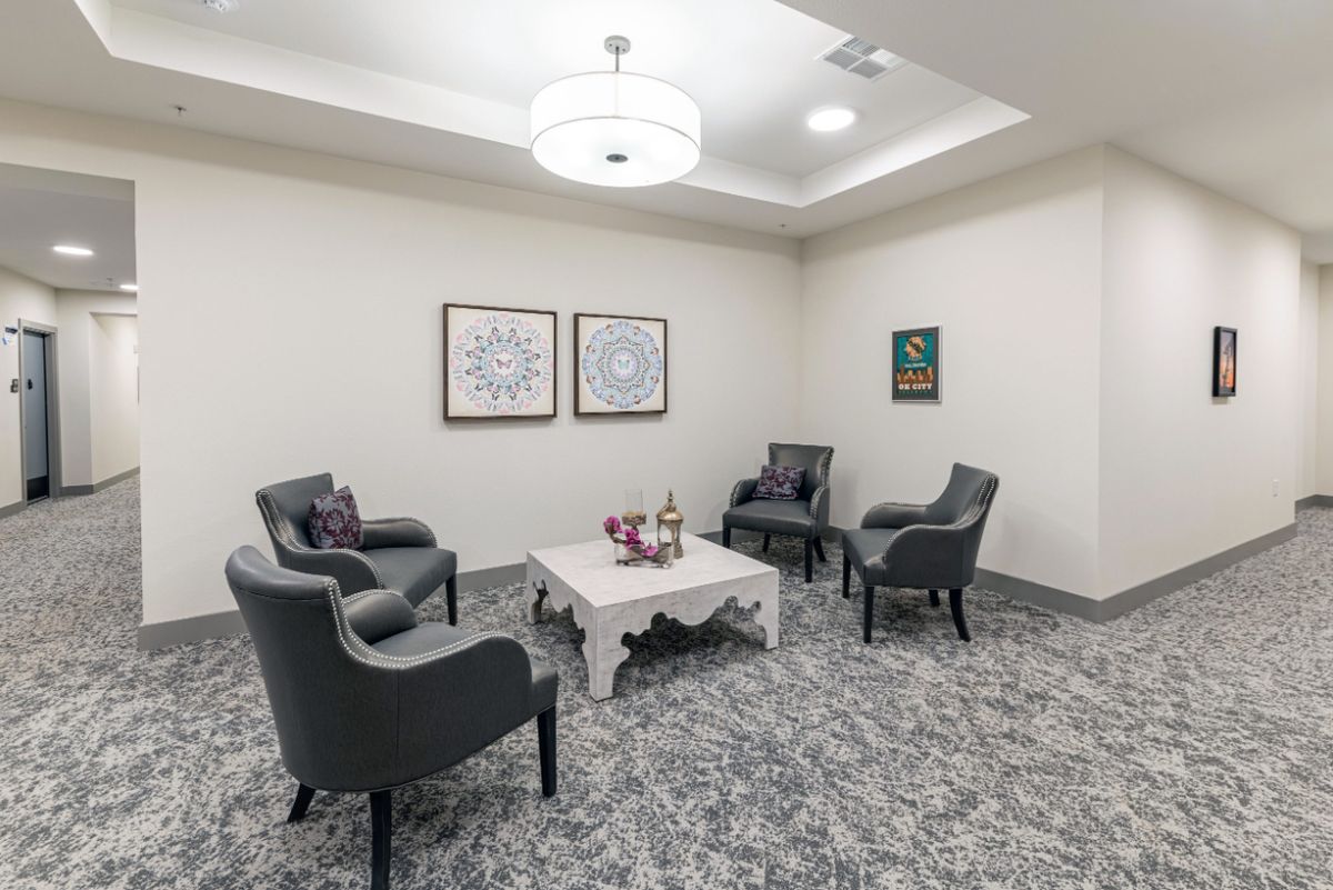 A cozy waiting room with elegant chairs and a coffee table under a modern light fixture.