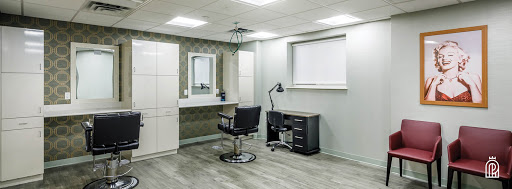 A modern salon interior featuring a barber chair, desk, and mirror.