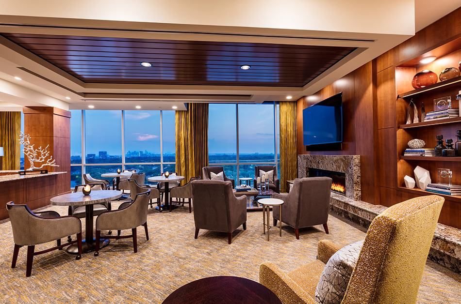A cozy lounge area with comfortable seating and a fireplace, offering a scenic view through large windows.