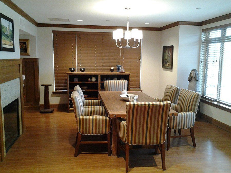 A dining room with a wooden table, striped chairs, and a chandelier overhead.