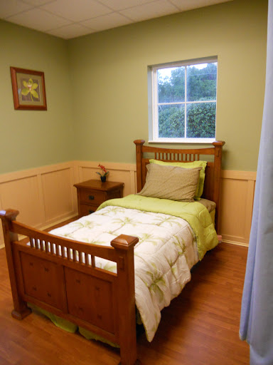 A cozy bedroom featuring a single wooden bed with green bedding and a serene ambiance.
