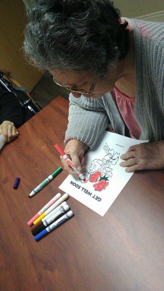 An adult is engaged in a coloring activity at a table using markers.