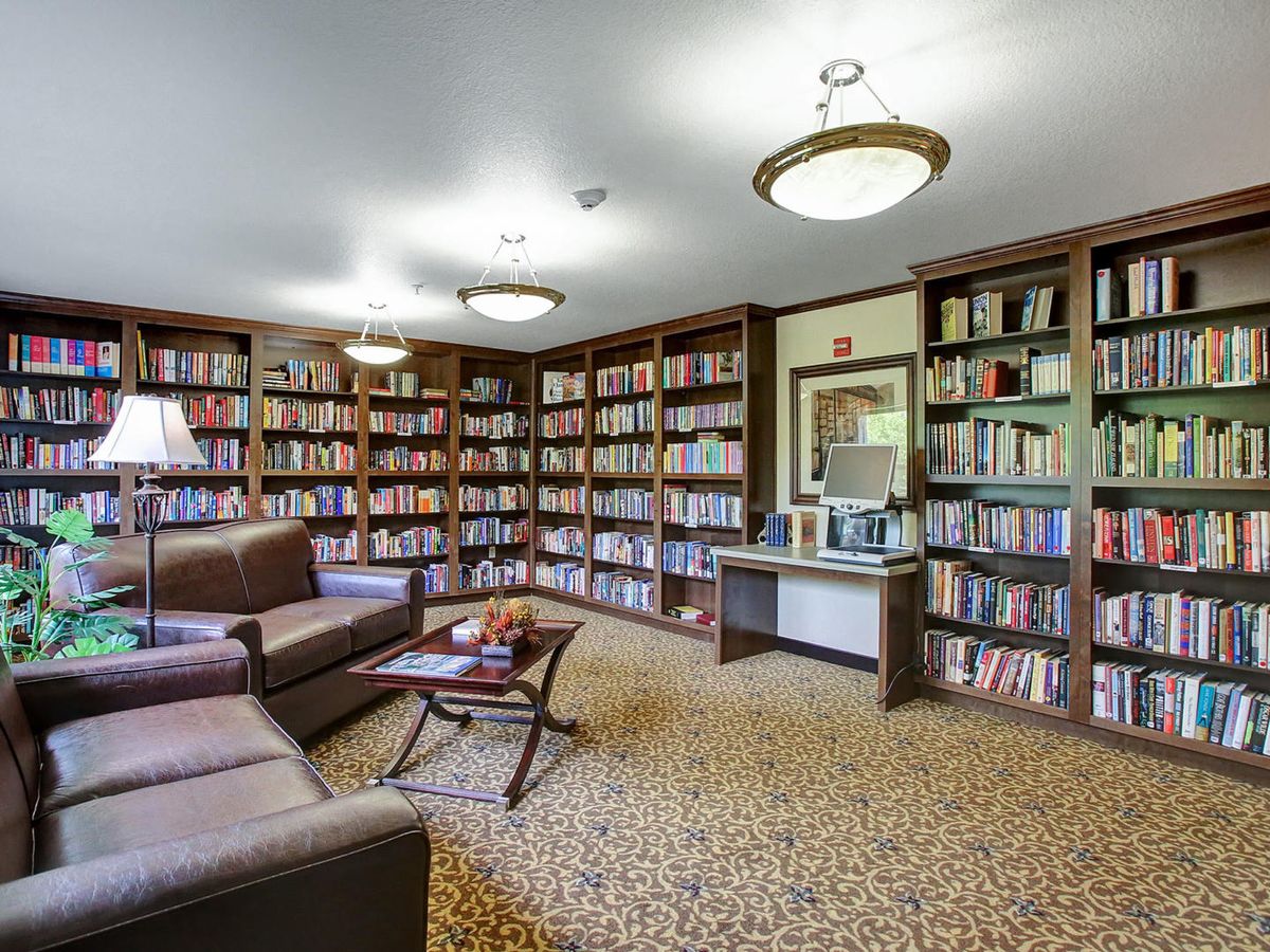 A cozy library with bookshelves, comfortable seating, and warm lighting.