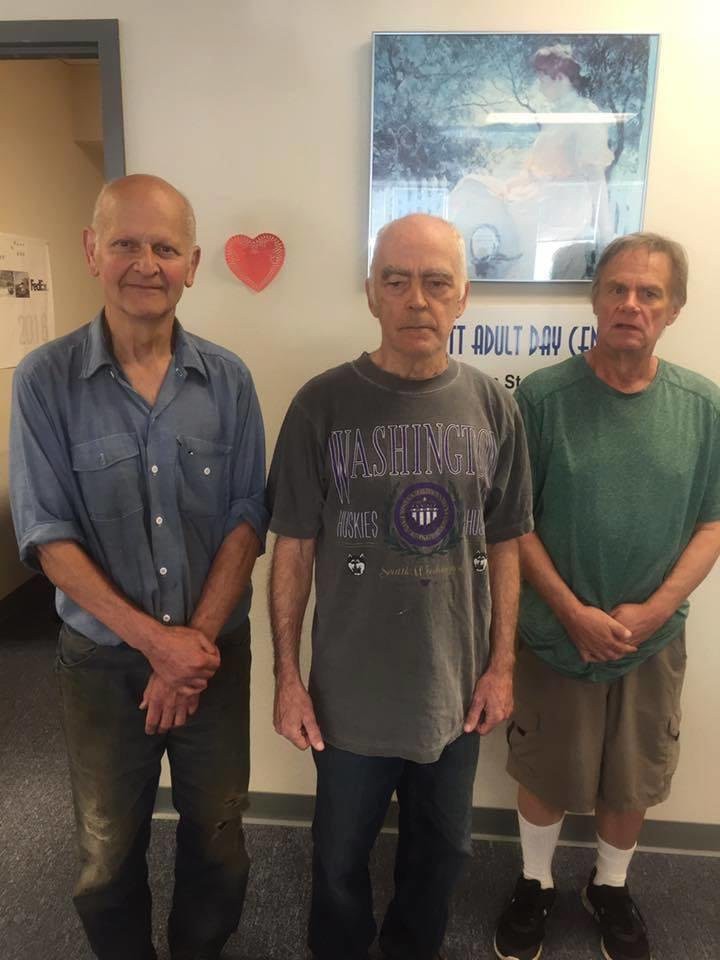 Three men standing indoors in casual attire.