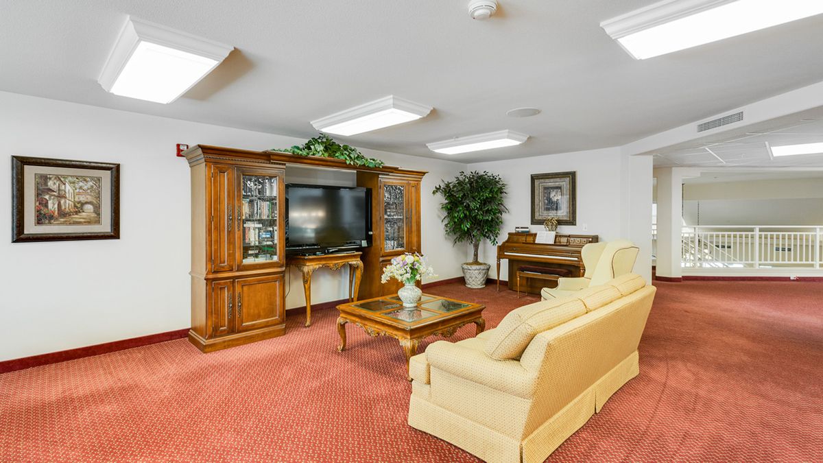 A cozy living room with vintage furniture, a television, and a piano.