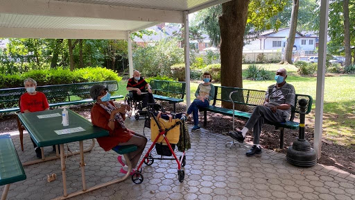 Elderly individuals enjoying a social gathering in a shaded outdoor area.