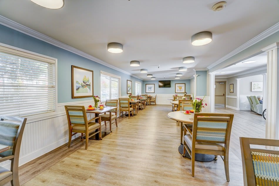 A well-lit dining area with wooden tables and chairs, featuring wall art and comfortable lighting.