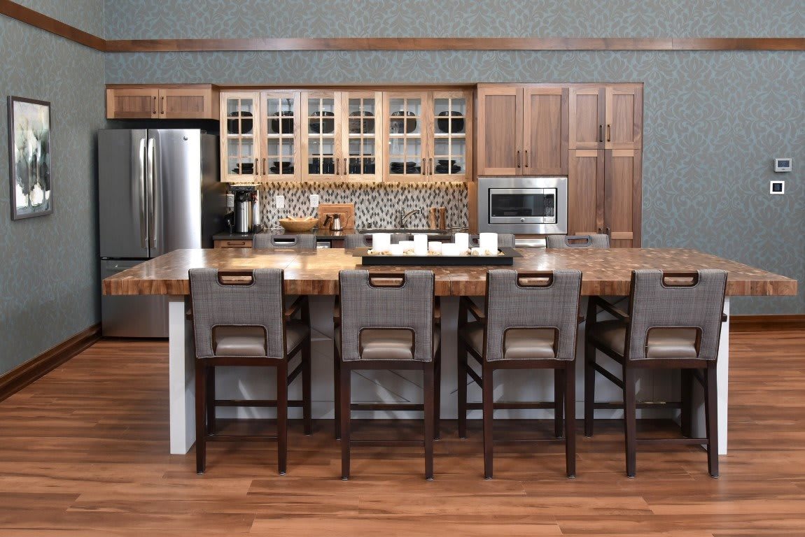 A modern kitchen with a large island and bar stools, featuring wood cabinets and stainless steel appliances.