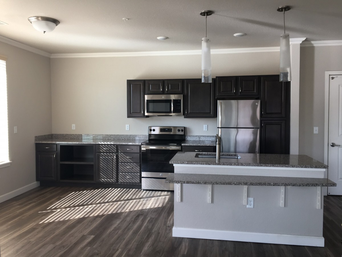 A modern kitchen with stainless steel appliances and wood flooring.