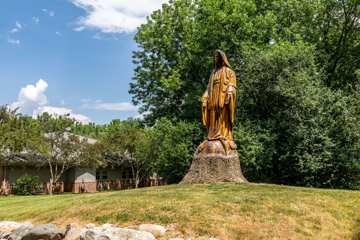 A large statue set in a natural landscape with lush greenery in the background.