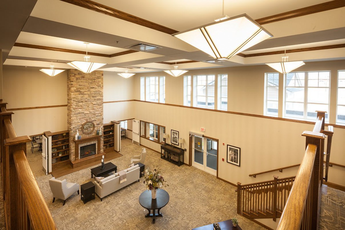 Spacious lobby area with modern lighting, comfortable seating, and a brick fireplace.