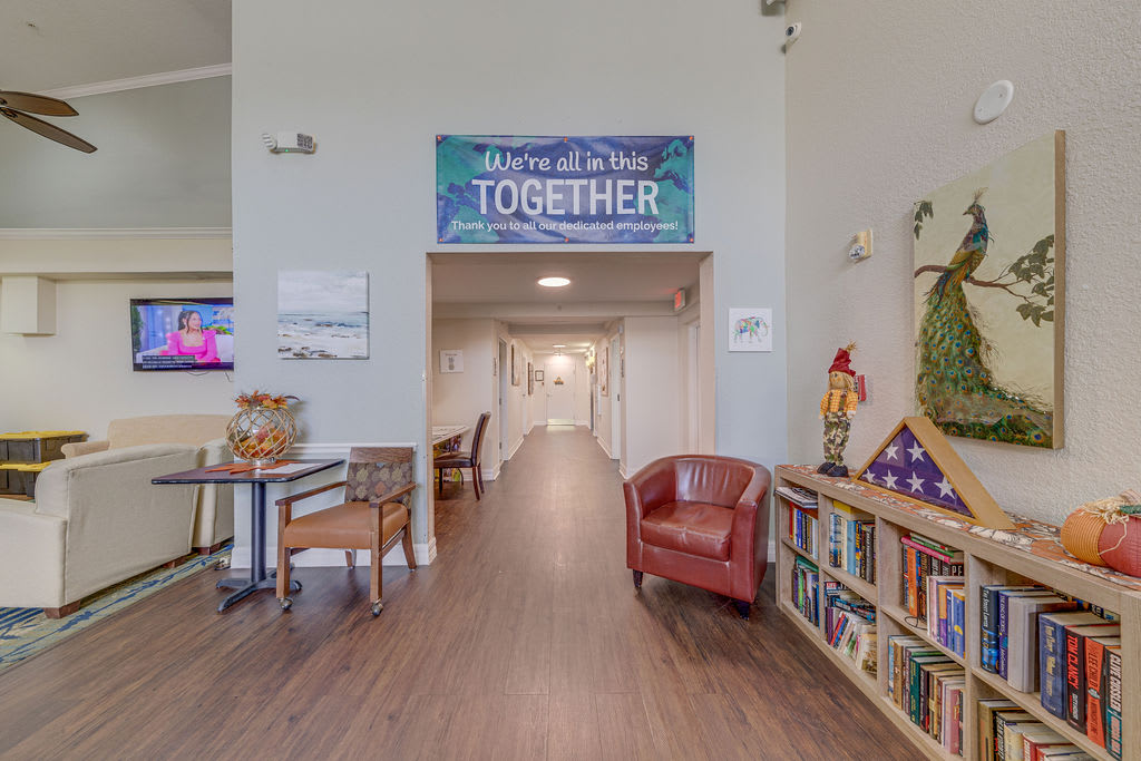 A welcoming community space featuring a bookshelf, seating area, and an inviting sign above the hallway.