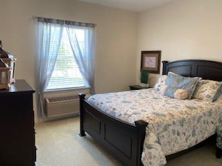 A cozy bedroom with a neatly-made bed and a window allowing natural light.