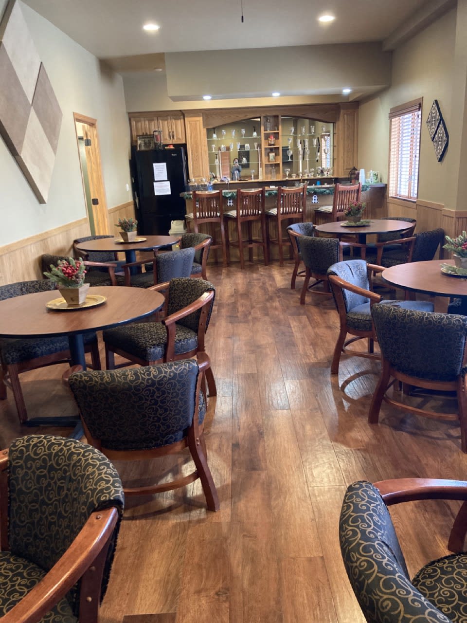 An empty dining area with tables and chairs, featuring a bar in the background.
