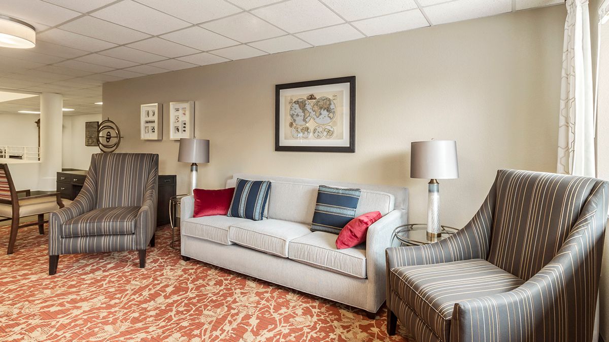 A cozy living room with a grey sofa, colorful cushions, and artistic wall decor.