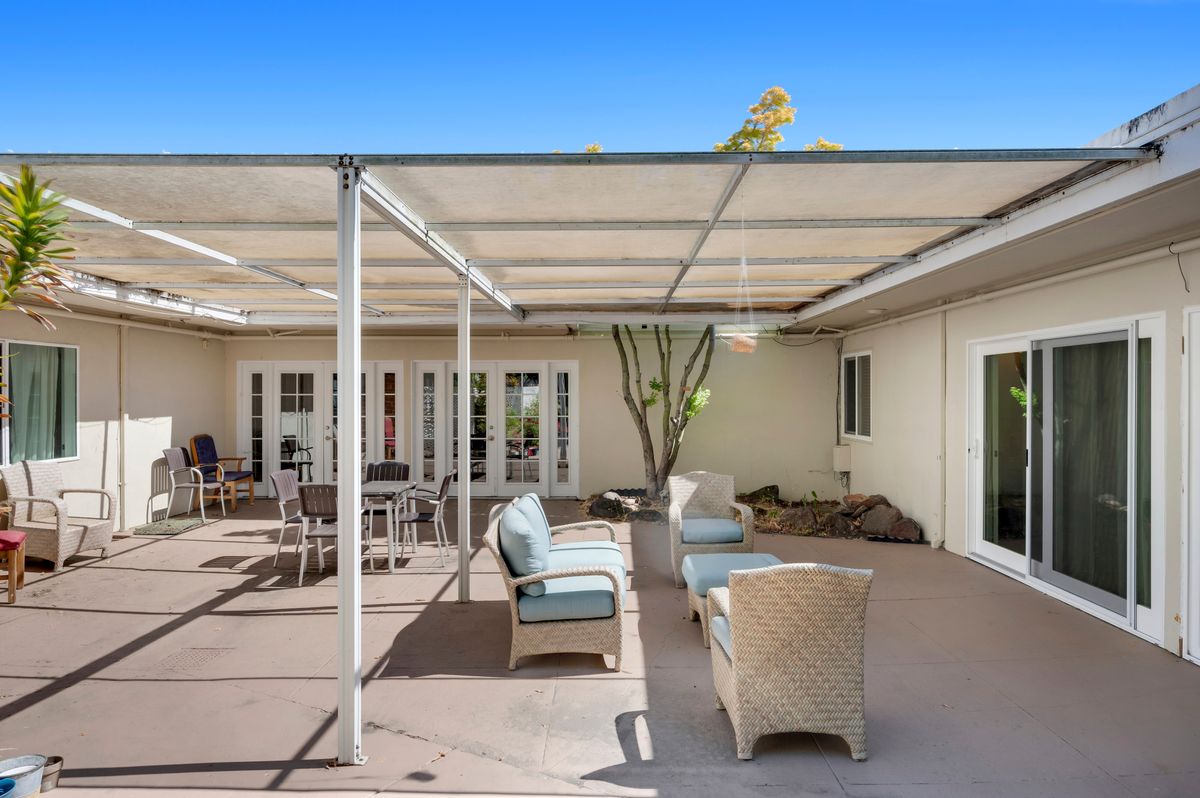 A sunny patio with comfortable outdoor seating and a pergola.