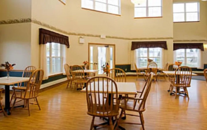 A bright and spacious dining room with wooden tables and chairs, surrounded by large windows.
