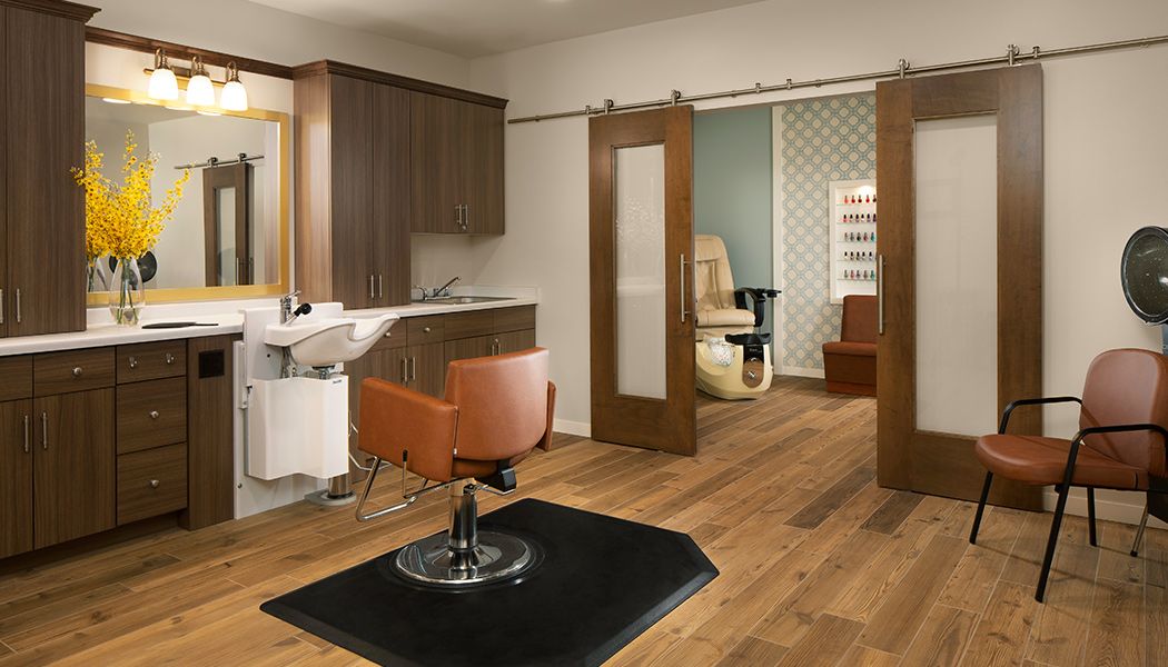 A modern salon interior with a hairdressing station and sliding doors leading to a private room.