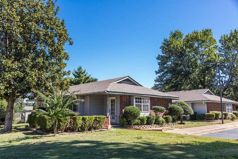 A suburban single-story house with a landscaped yard under a clear blue sky.