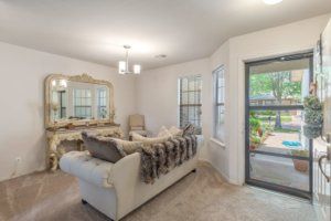 A cozy living room with a plush sofa, decorative mirror, and large windows opening to a patio.