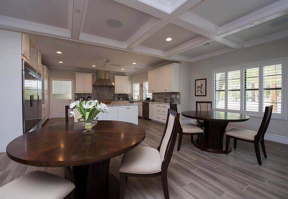 A modern dining area with an adjoining kitchen featuring elegant furniture and contemporary lighting.