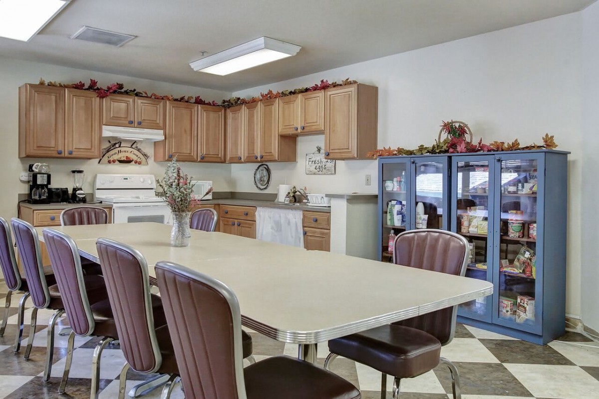 A spacious kitchen with a dining table, surrounded by cabinets and appliances.