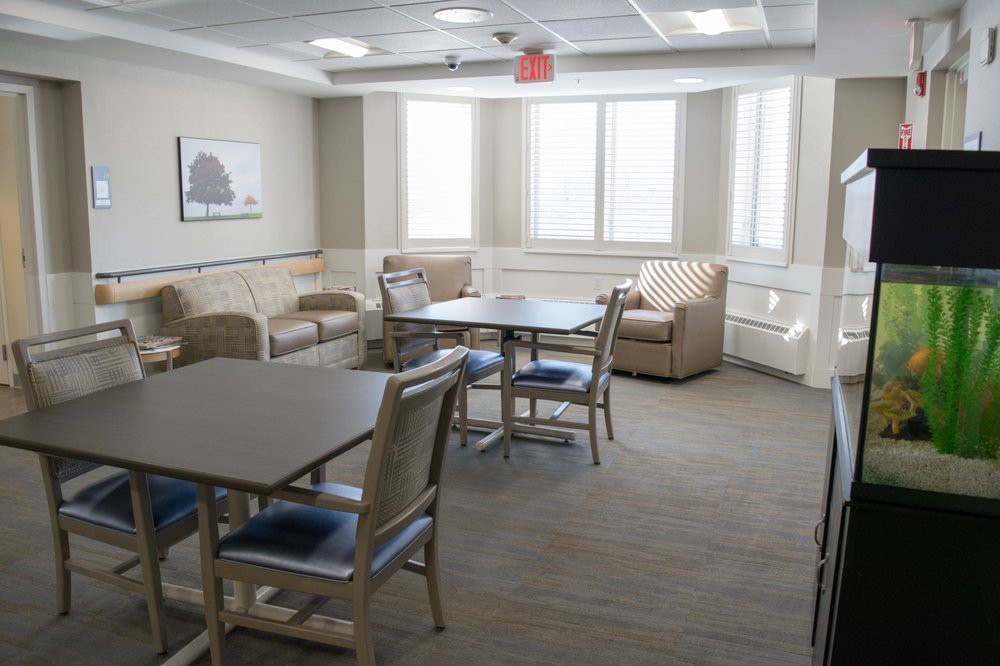 A cozy lounge area with tables, chairs, and sofas near large windows.