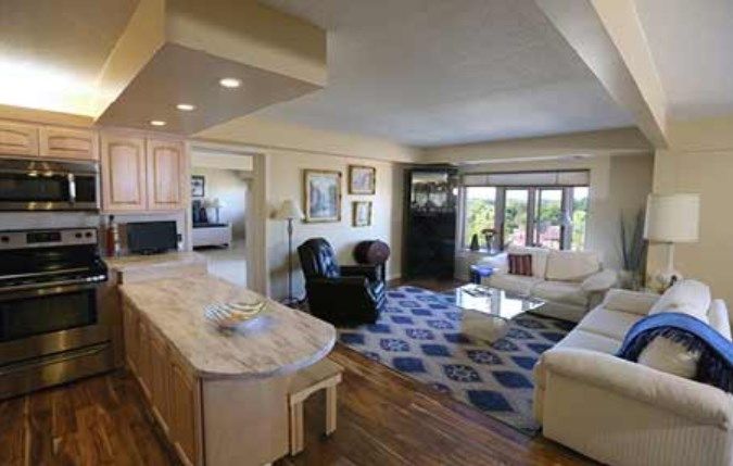 A cozy living room with stylish furniture and large windows, featuring a comfortable sofa, armchair, and a decorative rug.