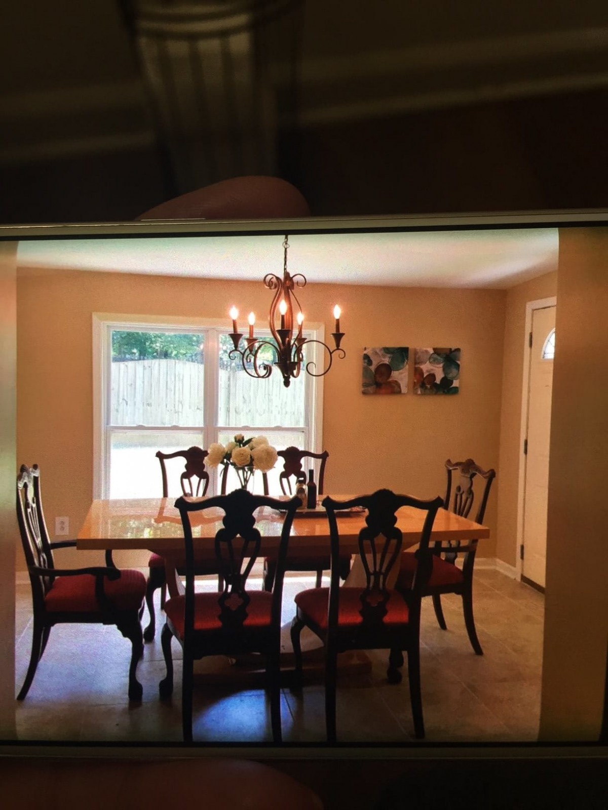 A dining room with a wooden table set, chairs, and a chandelier.
