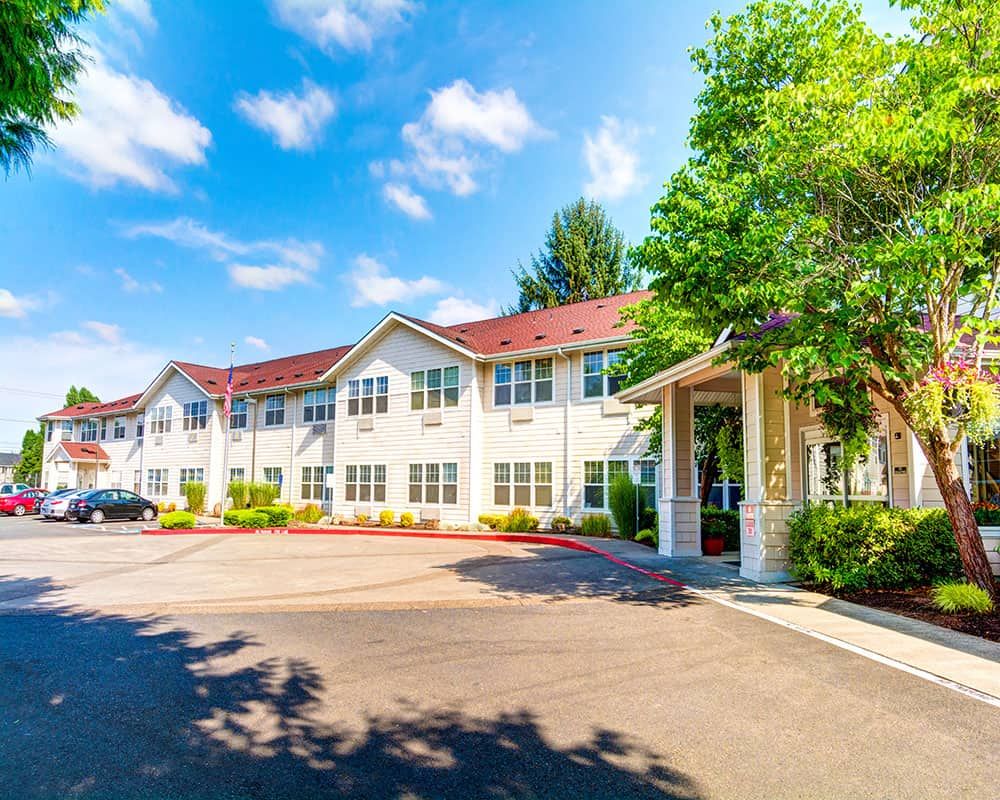 A sunny view of a residential building with trees and a clear blue sky.