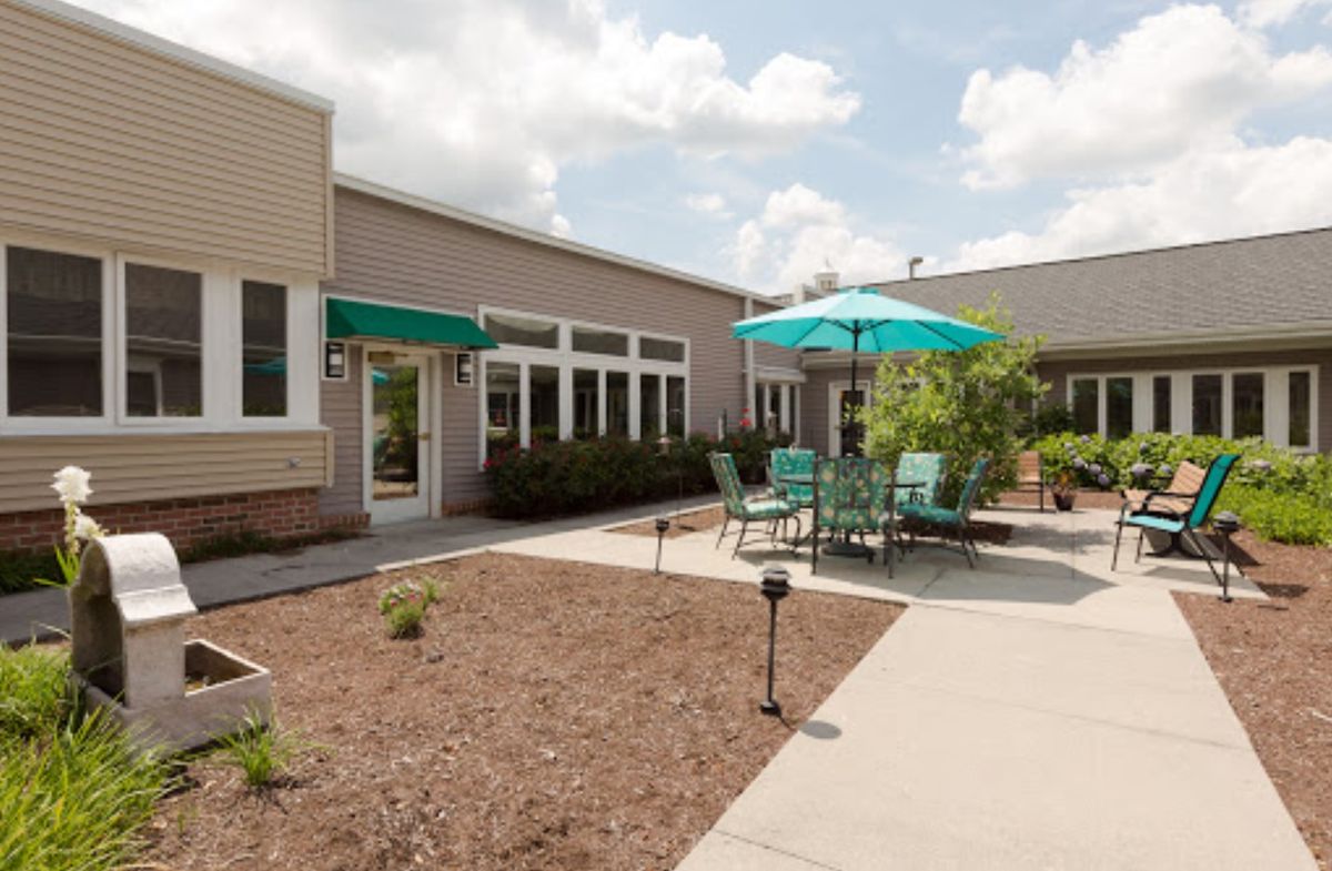 A sunny outdoor patio area with seating and umbrellas next to a building.