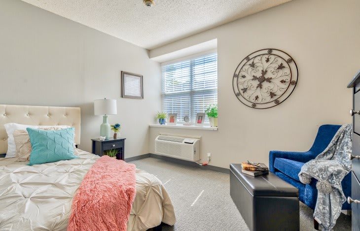 A modern bedroom with stylish decor, featuring a large clock and several potted plants by the window.