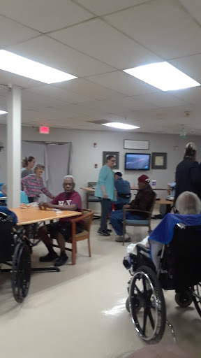 A lively common area in a senior living facility where residents engage with staff and each other.