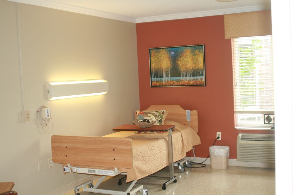 A hospital room with a single patient bed and warm-toned walls.