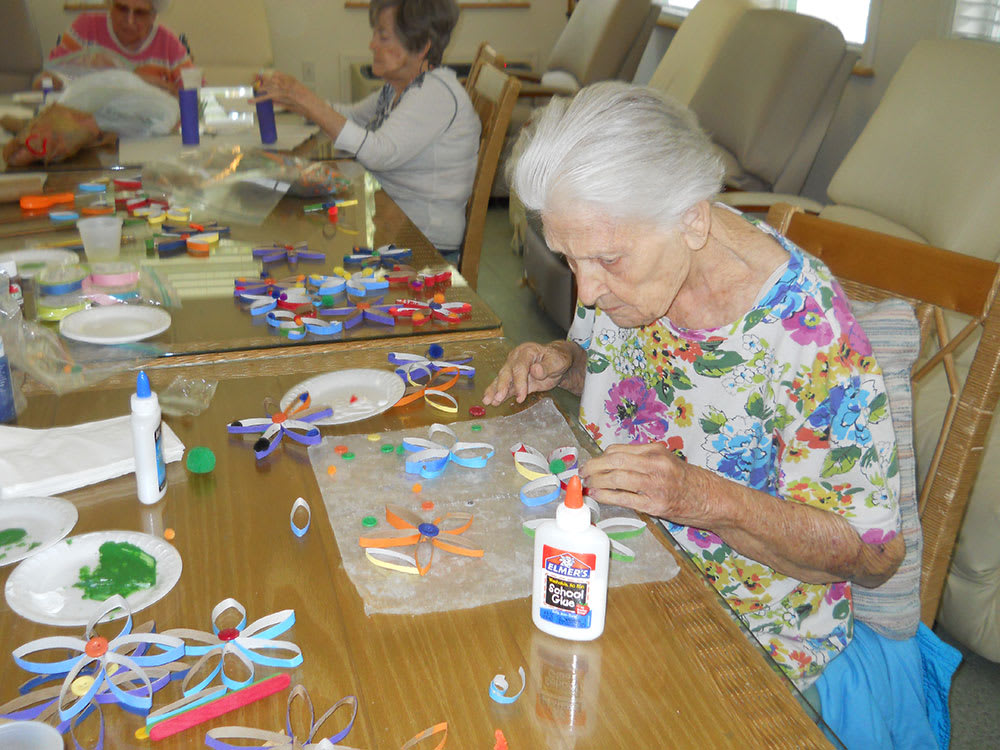 Elderly women engaging in arts and crafts activities at a table.