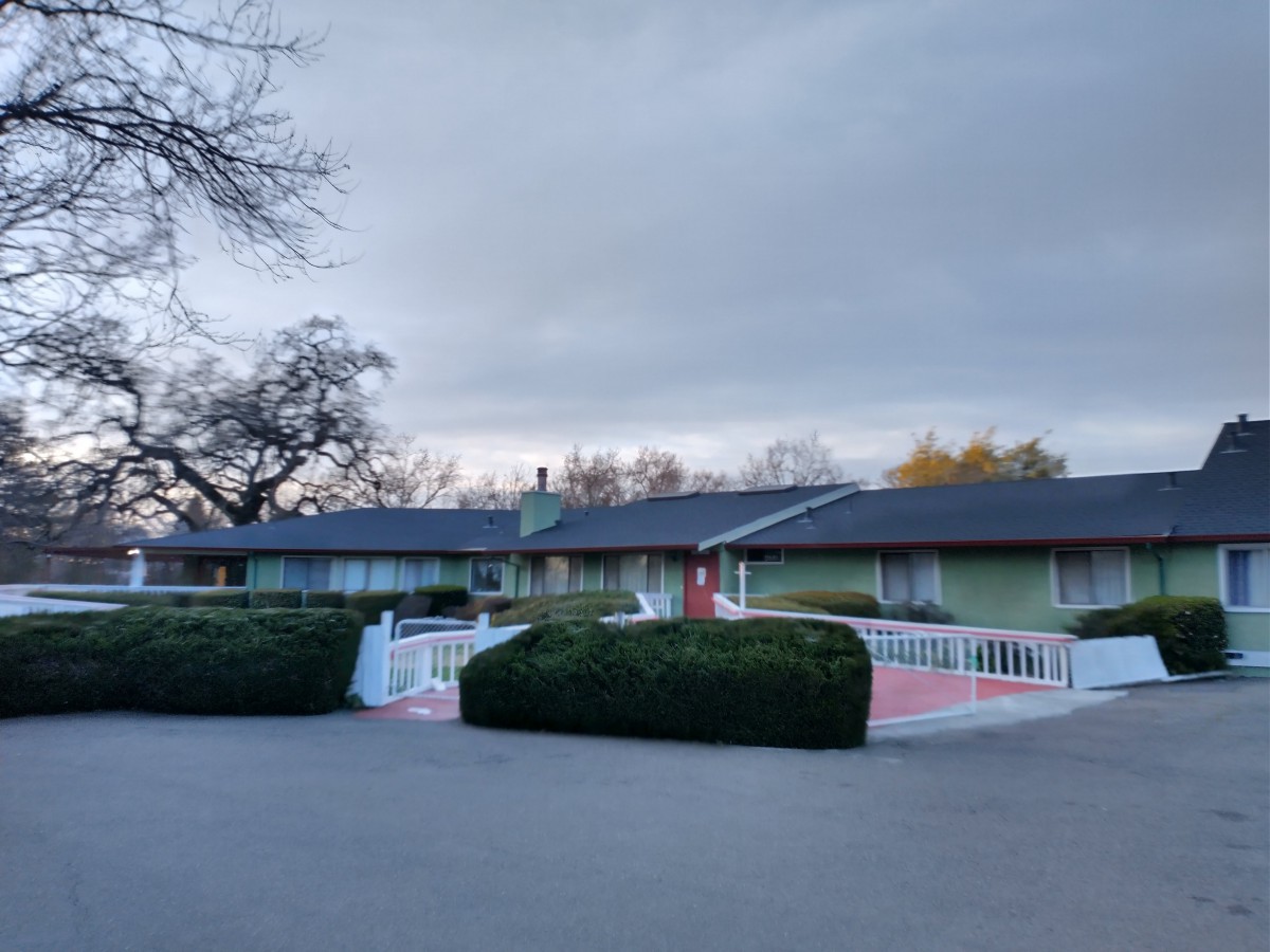 A view of a motel building with overcast skies and landscaped shrubs.