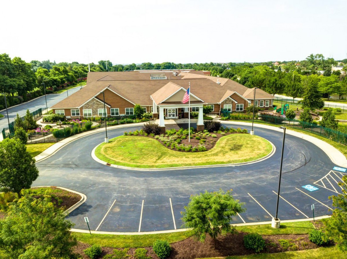 Aerial view of a suburban building with a circular driveway and landscaped surroundings.