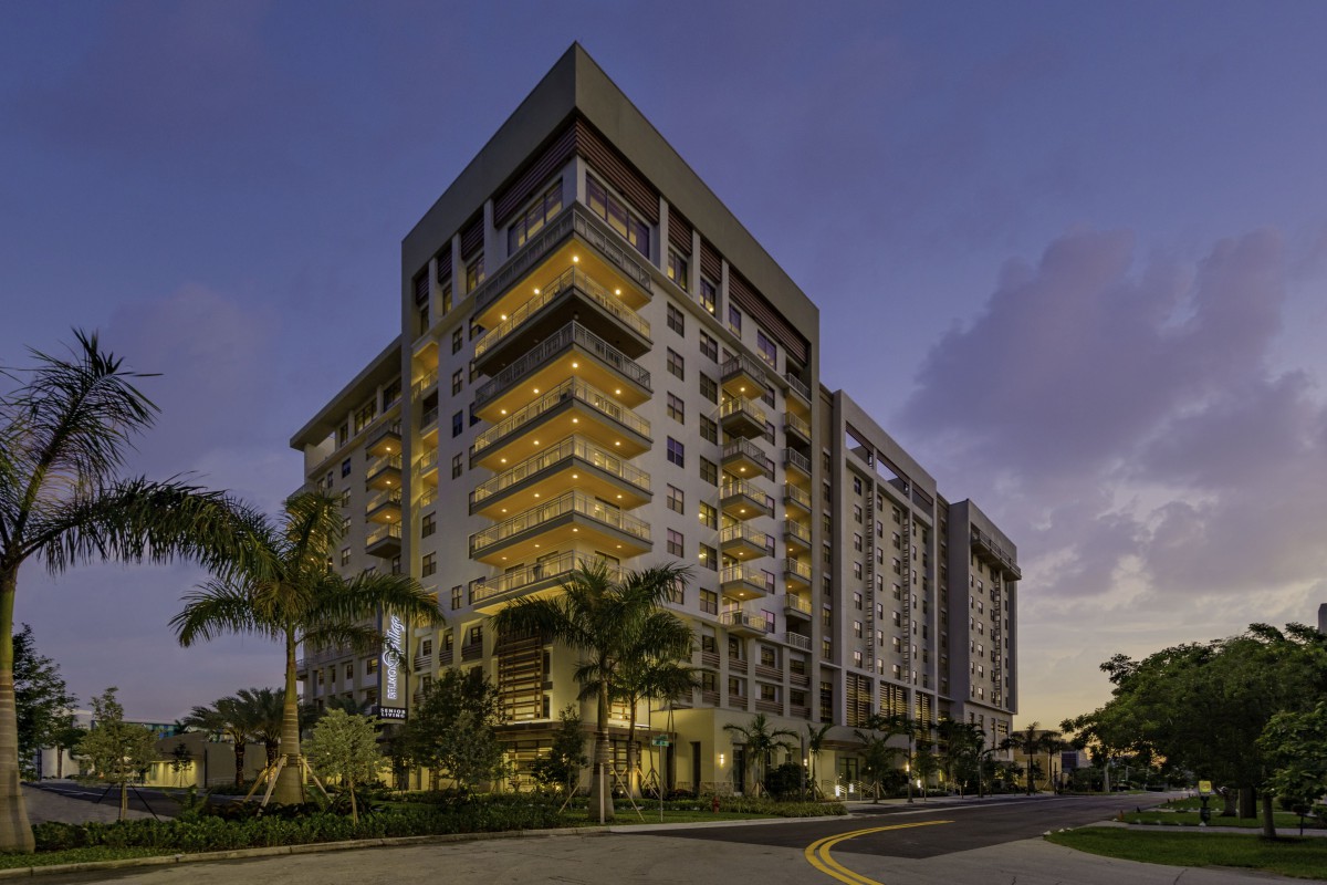 A modern condominium building illuminated during the evening, showcasing its architectural design.