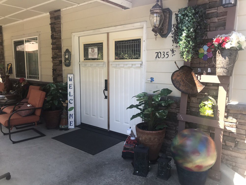A welcoming front porch with double doors, surrounded by potted plants and cozy outdoor decorations.